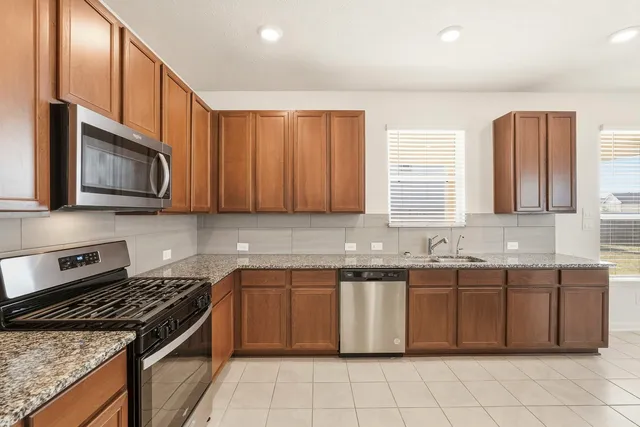 a kitchen with stainless steel appliances granite countertop a stove a sink and a microwave