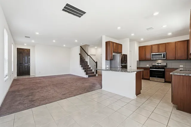 a large kitchen with stainless steel appliances kitchen island granite countertop a refrigerator and microwave
