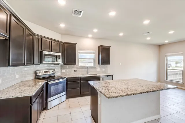 a kitchen with stainless steel appliances granite countertop a sink counter space cabinets and a large window