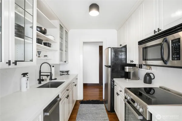 a kitchen with stainless steel appliances granite countertop a sink a stove and a refrigerator with wooden floor