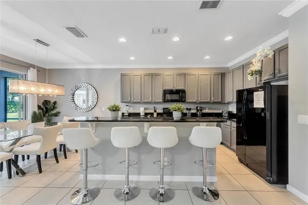 a kitchen with stainless steel appliances granite countertop a stove top oven a sink a dining table and chairs
