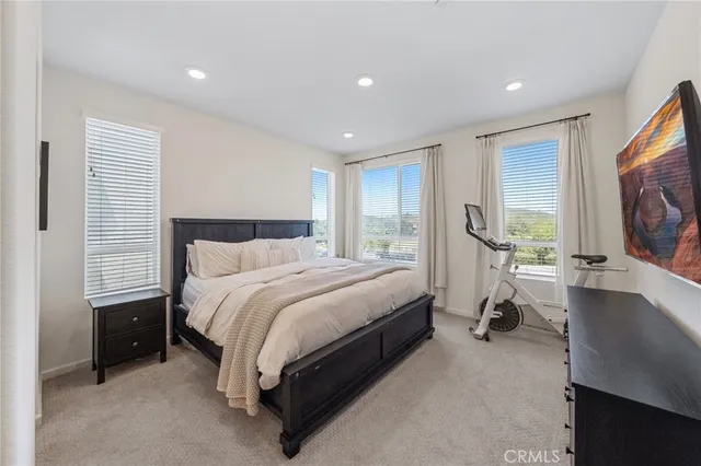 a spacious bedroom with a bed and a flat screen tv