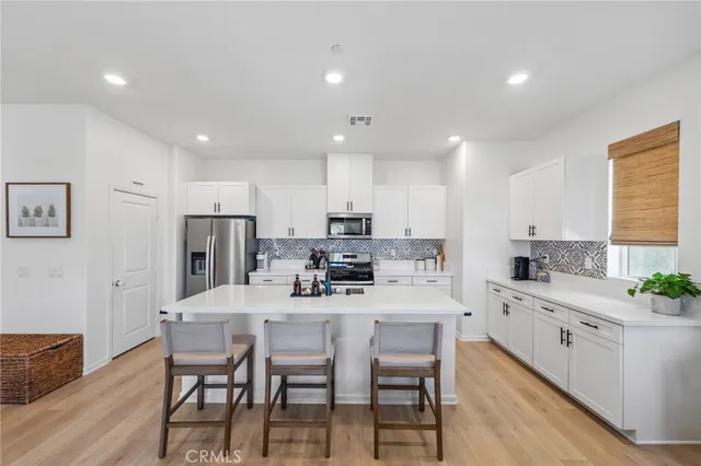 a kitchen with stainless steel appliances kitchen island granite countertop a dining table chairs and sink