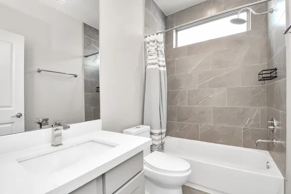 a bathroom with a bathtub shower sink vanity mirror and toilet