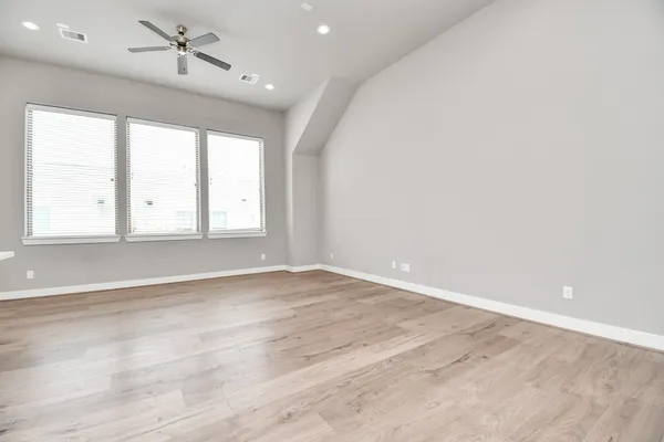 an empty room with wooden floor and windows