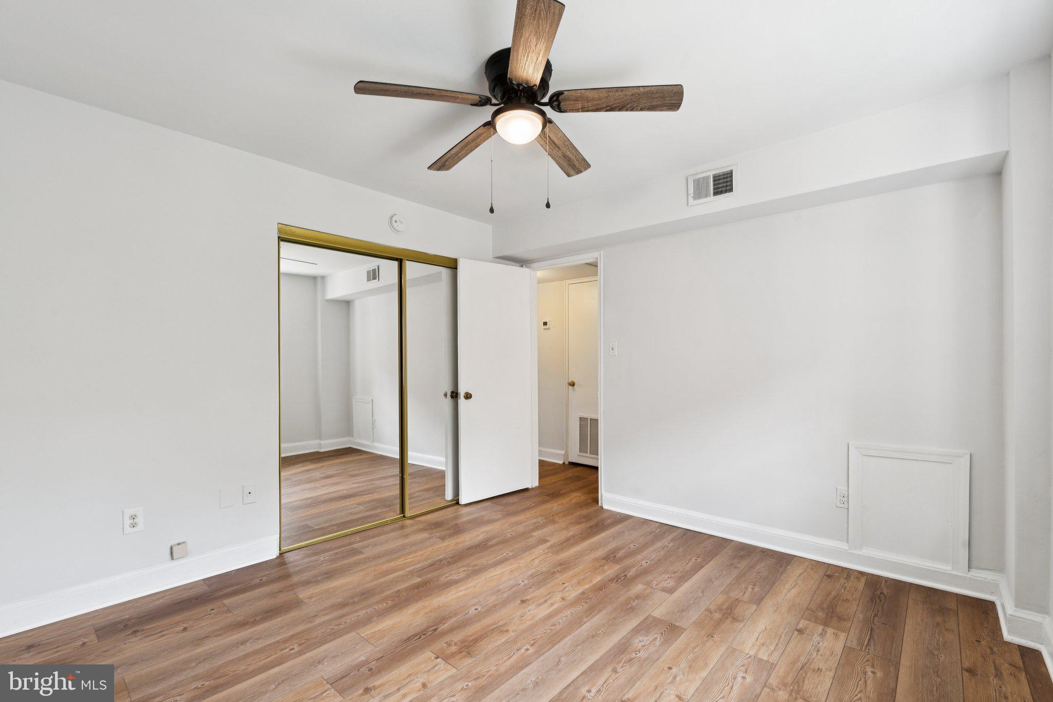2107 North Scott Street, Unit 70 Arlington, VA 22209 - Photo 12 of 19 an empty room with wooden floor chandelier fan and windows