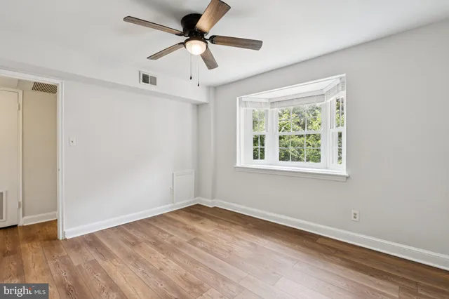 a view of empty room with wooden floor and fan