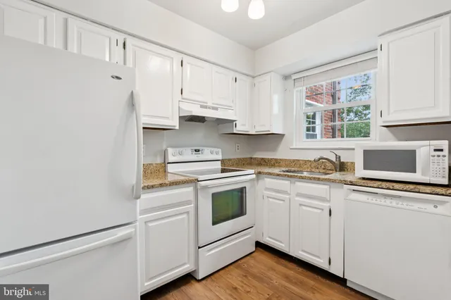a kitchen with white cabinets white stainless steel appliances and sink