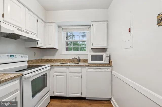 a kitchen with granite countertop white cabinets and white appliances