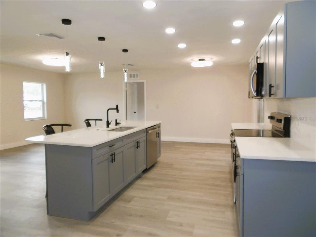 614 Huntington Street Brandon, FL 33511 - Photo 6 of 16 a large white kitchen with a sink and dishwasher a stove top oven with wooden floor