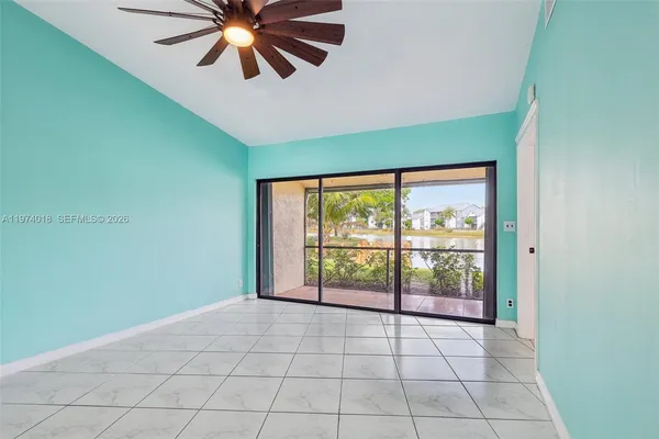 a view of an empty room with window and chandelier fan