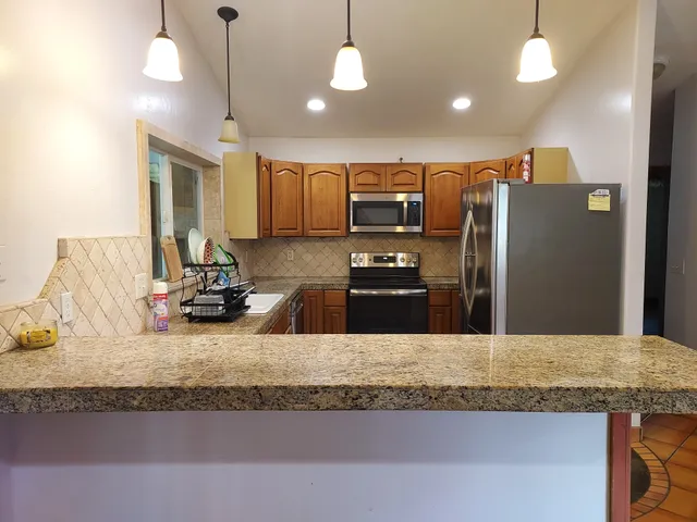 a kitchen with stainless steel appliances granite countertop a sink a stove and a refrigerator