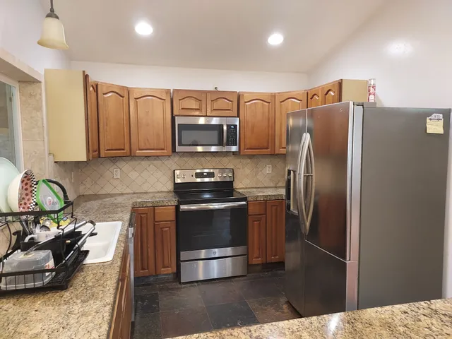 a kitchen with stainless steel appliances granite countertop a stove a sink and a refrigerator
