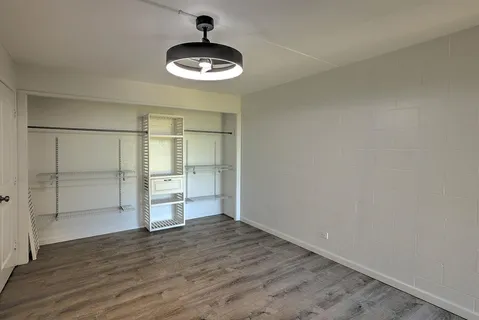 an empty room with wooden floor closet and windows