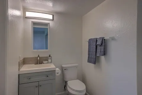 a bathroom with a toilet sink vanity and mirror