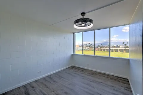 a view of an empty room with a window and wooden floor