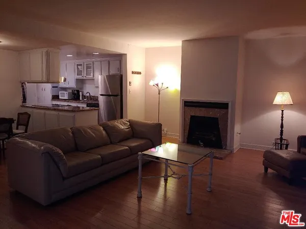 a kitchen with stainless steel appliances granite countertop a stove a refrigerator a sink a dining table and chairs with wooden floor