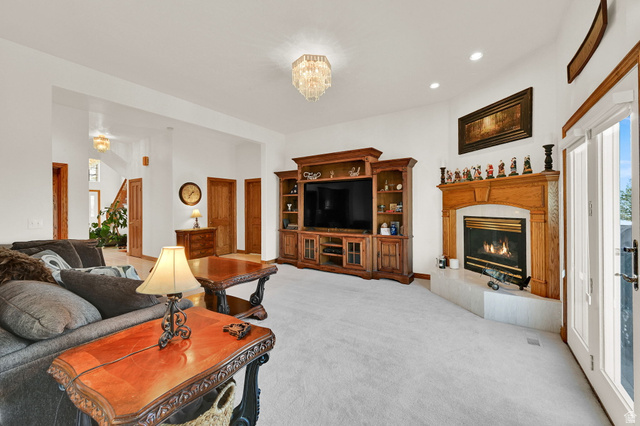 1085 Windsor Drive Provo, UT 84604 - Photo 11 of 83 Living area with a glass covered fireplace, light colored carpet, recessed lighting, and a chandelier