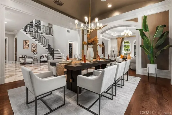 a dining room with wooden floor a chandelier a wooden table and chairs