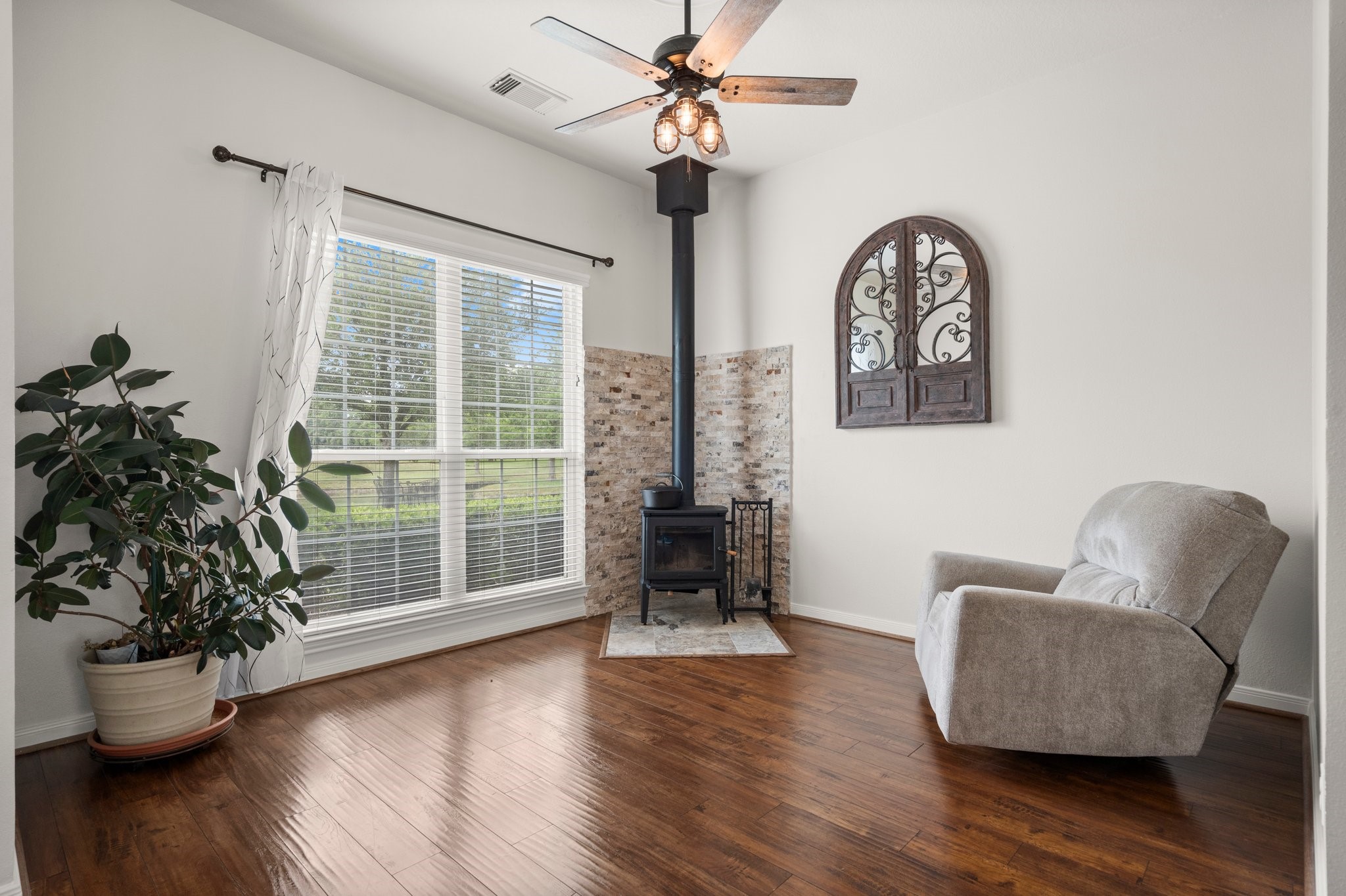 34334 Howell Road Waller, TX 77484 - Photo 11 of 37 Cozy living area with a charming wood-burning stove, hardwood floors, and ample natural light.