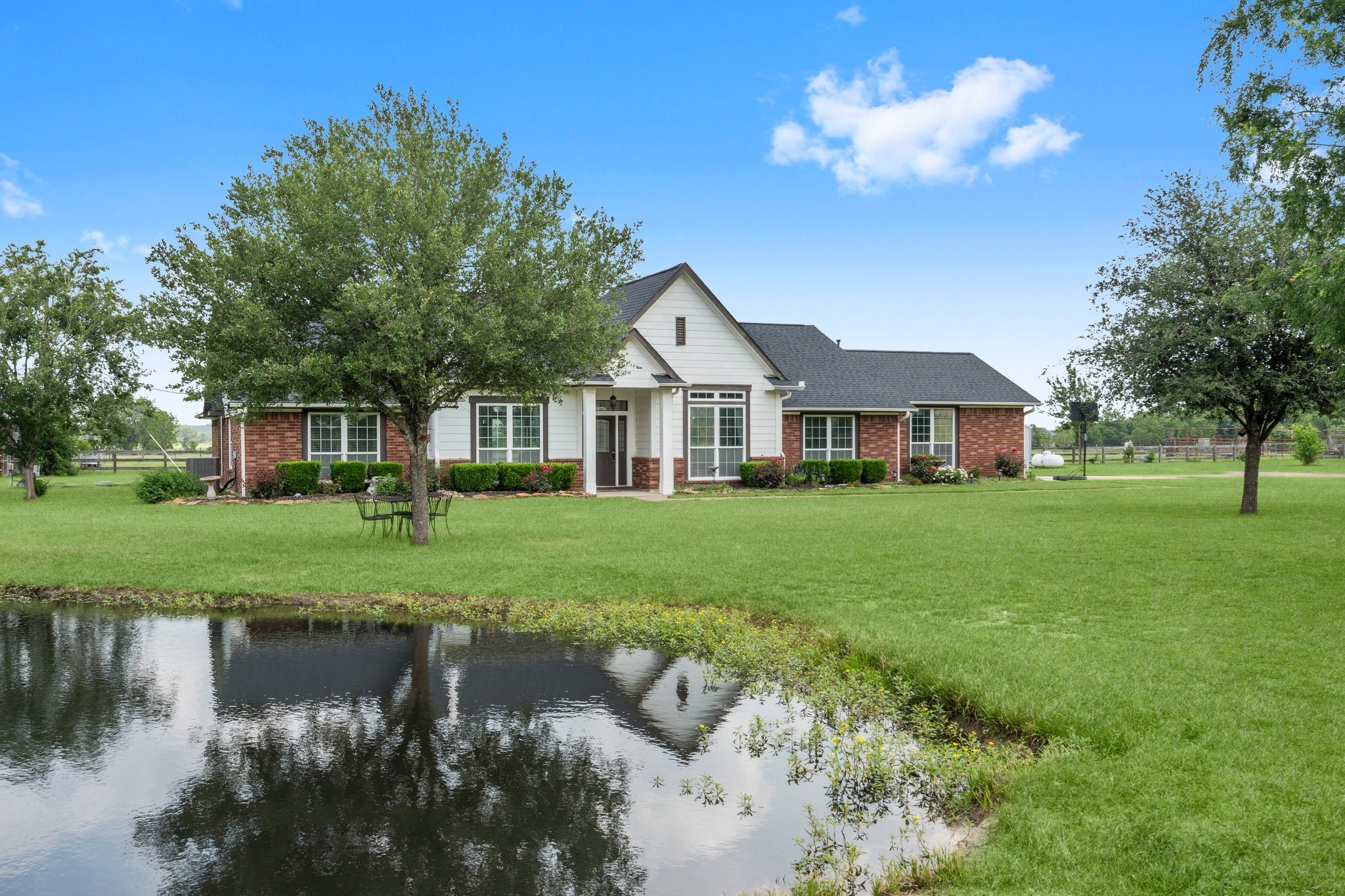 34334 Howell Road Waller, TX 77484 - Photo 2 of 37 Charming home with a serene pond and expansive lawn, offering a peaceful and picturesque setting.