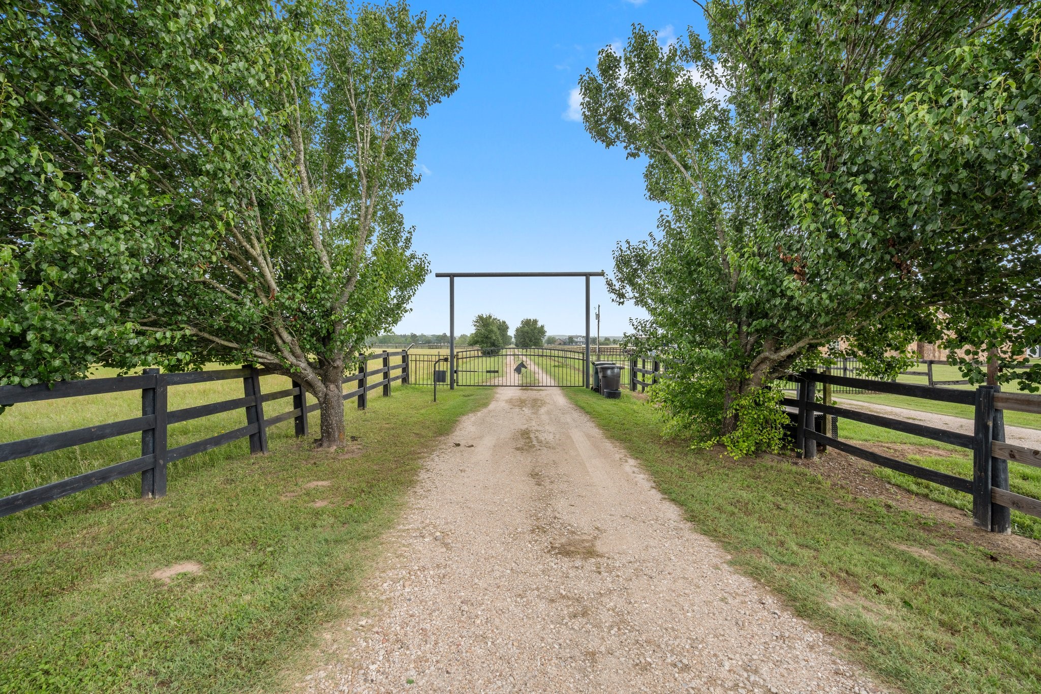 34334 Howell Road Waller, TX 77484 - Photo 4 of 37 Enjoy the peace and privacy offered by this secluded property. The gated entrance and long driveway are framed by mature trees and fencing, creating a tranquil and picturesque setting.