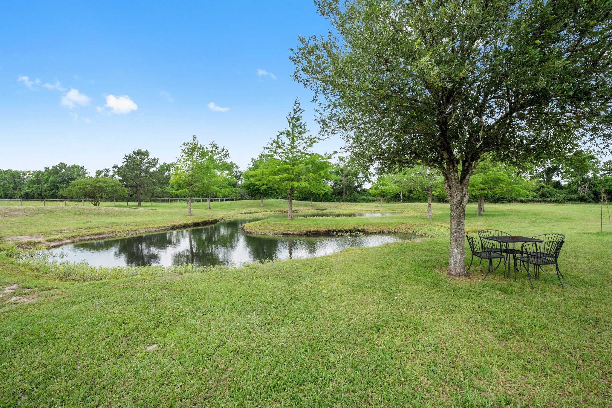 34334 Howell Road Waller, TX 77484 - Photo 5 of 37 Relax and unwind in this beautiful backyard featuring a tranquil pond and a charming seating area. It's the perfect spot to enjoy the natural beauty of your surroundings.