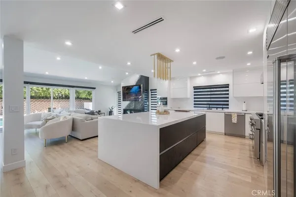 a large kitchen with kitchen island a large counter top space a sink a stove and a large window