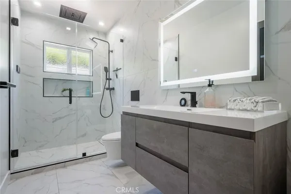 a bathroom with a shower sink mirror and toilet