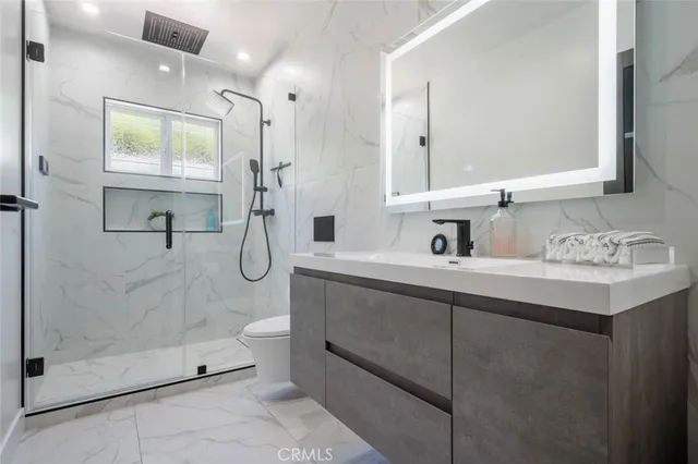 a bathroom with a shower sink mirror and toilet