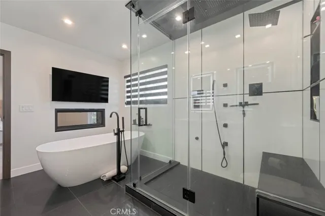a bathroom with a tub a mirror and a shower