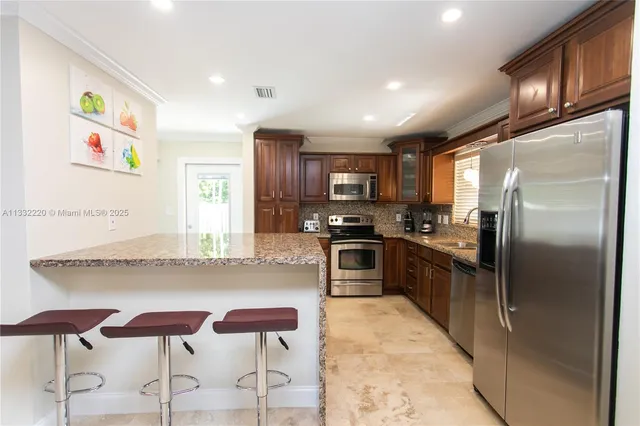 a kitchen with stainless steel appliances granite countertop a refrigerator and a stove top oven