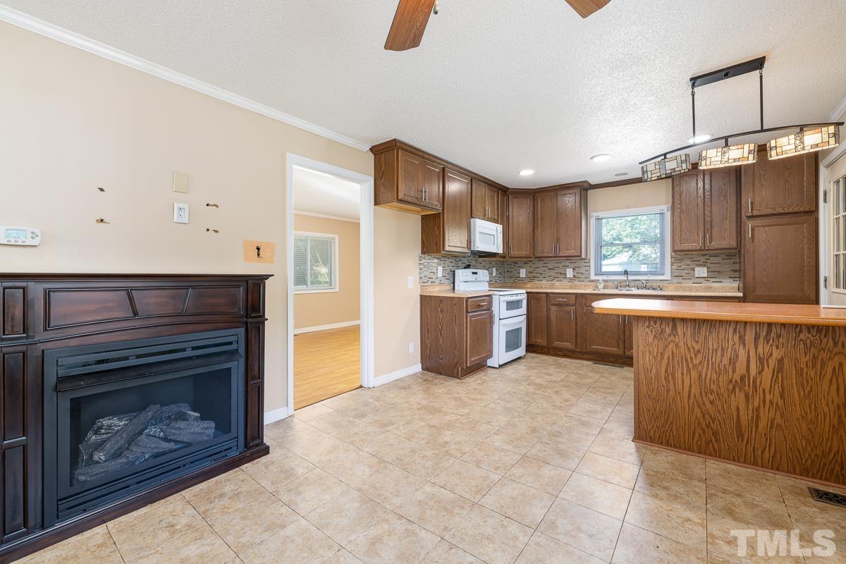 135 Goodwin Road Durham, NC 27712 - Photo 20 of 30 a kitchen with stainless steel appliances granite countertop a refrigerator a stove a sink dishwasher and a fireplace with wooden floor