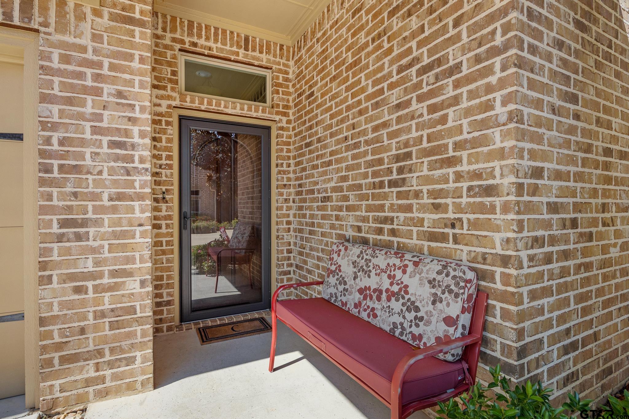 4322 Madera Drive Tyler, TX 75707 - Photo 3 of 32 a brick building with a bench and a potted plant