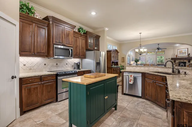 a kitchen with kitchen island granite countertop a sink stove and refrigerator