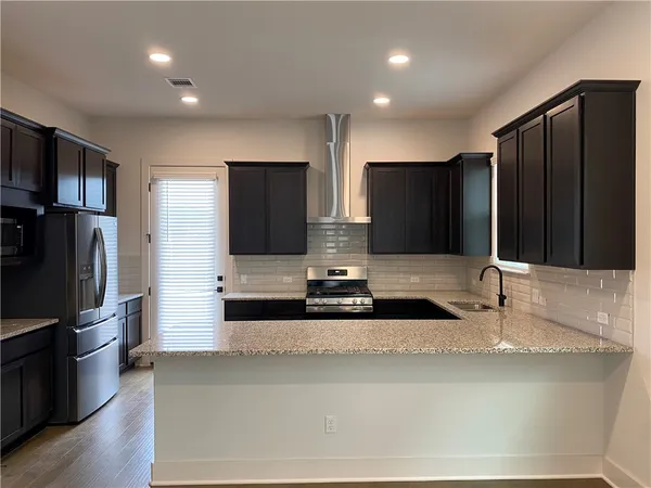 a kitchen with stainless steel appliances granite countertop a refrigerator and a sink