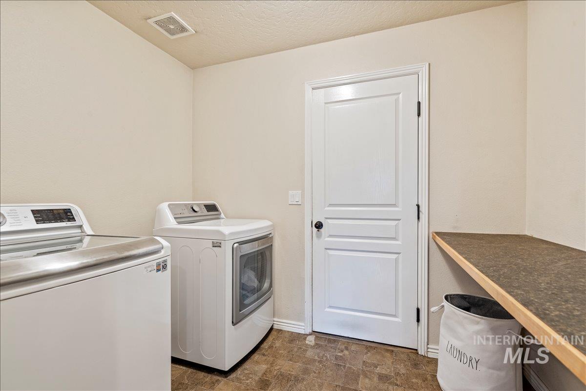 12293 West Murchison Street Boise, ID 83709 - Photo 13 of 27 Washroom featuring stone finish floors, washer and clothes dryer, and a textured ceiling