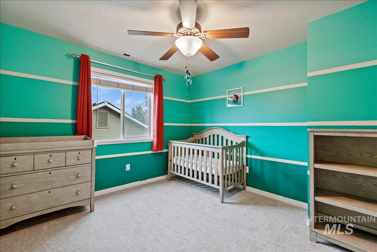 12293 West Murchison Street Boise, ID 83709 - Photo 21 of 27 Bedroom with light colored carpet, a crib, a ceiling fan, and a textured ceiling