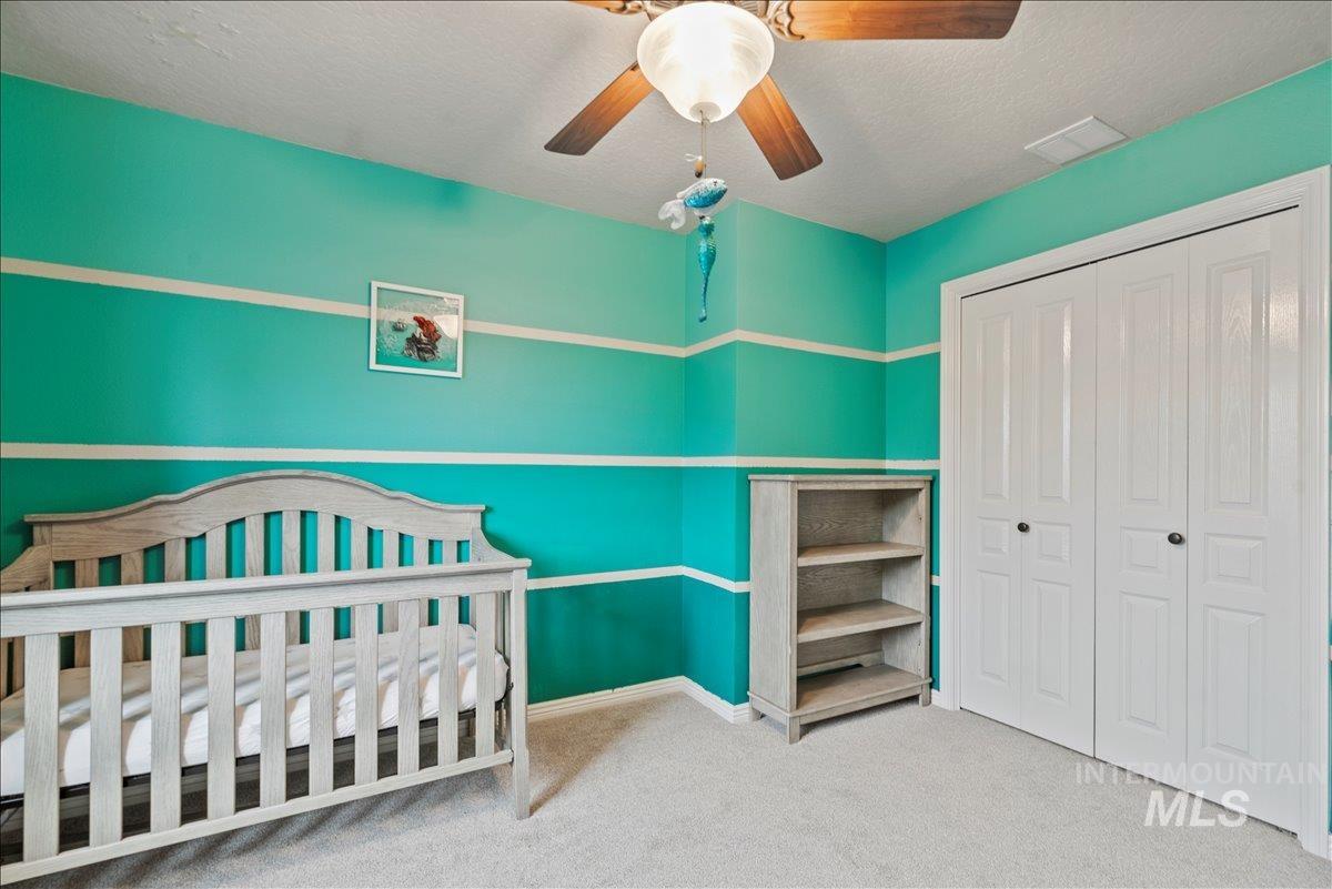 12293 West Murchison Street Boise, ID 83709 - Photo 22 of 27 Bedroom with light colored carpet, a textured ceiling, a closet, a ceiling fan, and a nursery area