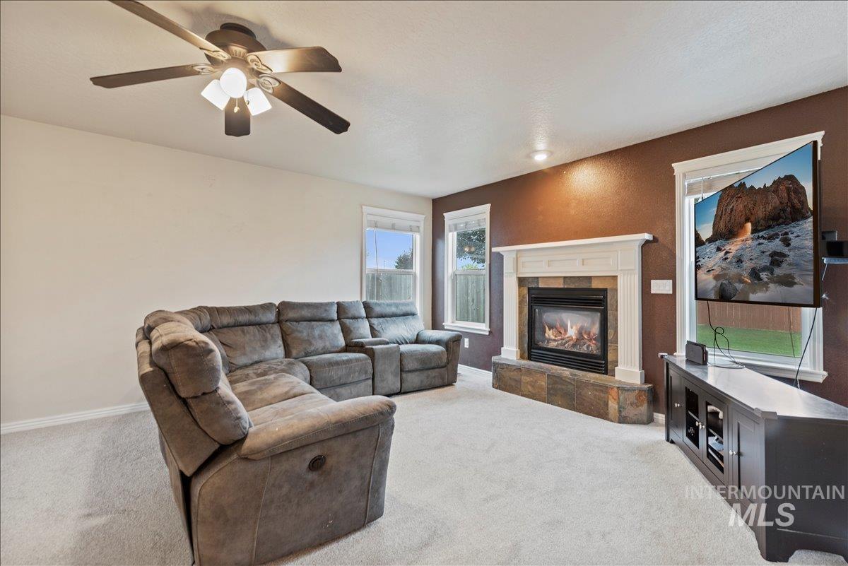 12293 West Murchison Street Boise, ID 83709 - Photo 3 of 27 Living room with light colored carpet, a tiled fireplace, and a ceiling fan