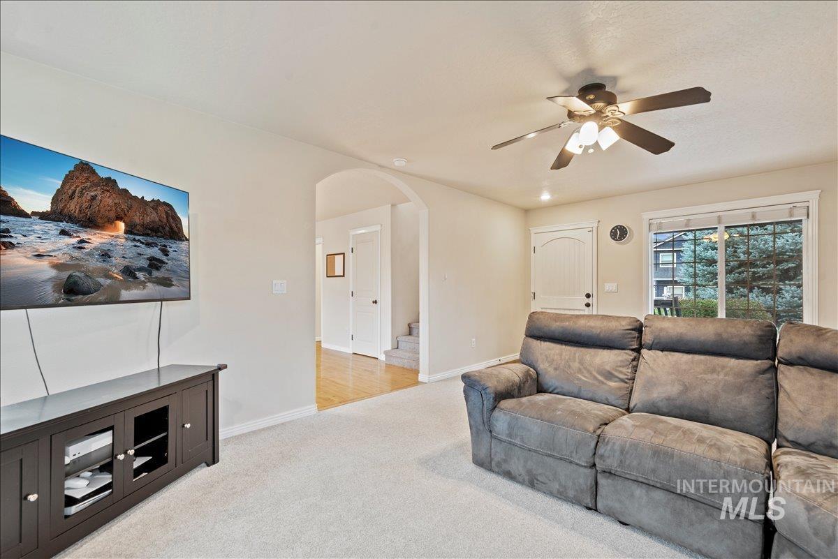 12293 West Murchison Street Boise, ID 83709 - Photo 6 of 27 Living area featuring light colored carpet, arched walkways, ceiling fan, and stairs