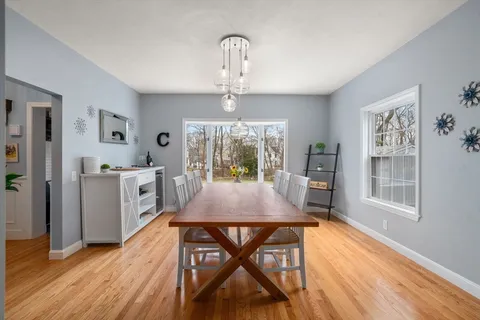 a dining room with wooden floor a chandelier a wooden table and chairs