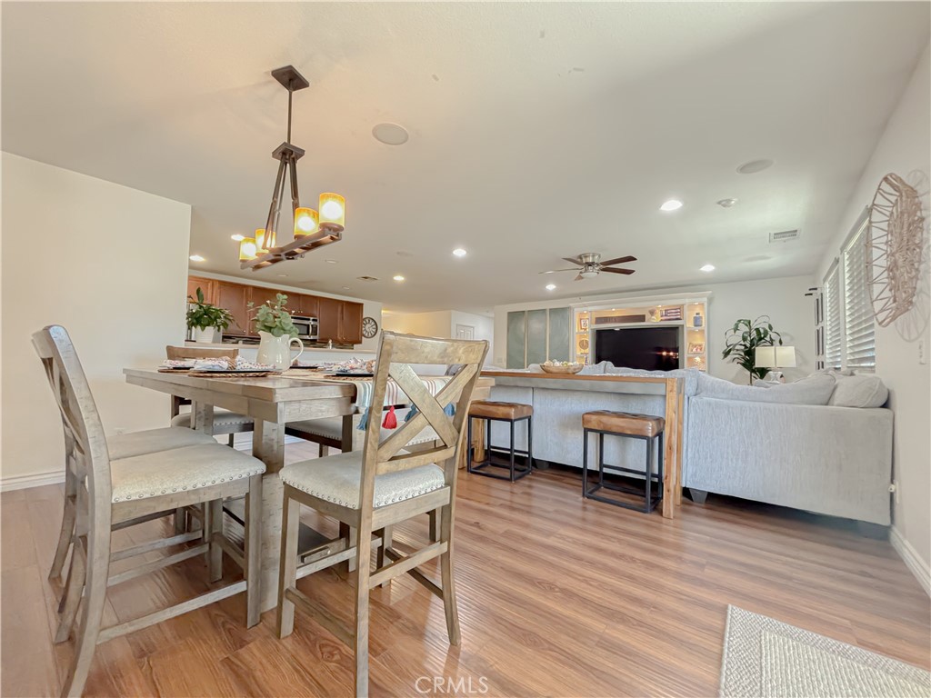 3345 James Court Lancaster, CA 93535 - Photo 11 of 29 a view of a dining room and livingroom with furniture wooden floor a rug a flat screen tv a painting and a chandelier