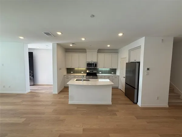 a view of kitchen with stainless steel appliances refrigerator stove microwave and cabinets