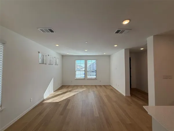 an empty room with wooden floor and windows
