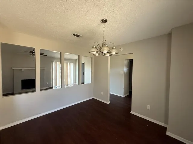 a view of a livingroom with a chandelier fireplace and wooden floor