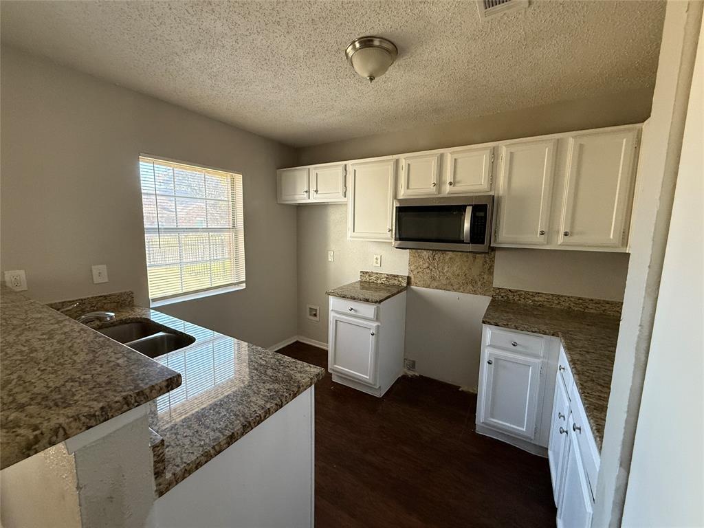 375 Ancestry Lane Dallas, TX 75217 - Photo 7 of 19 a kitchen with granite countertop a stove a sink and a microwave