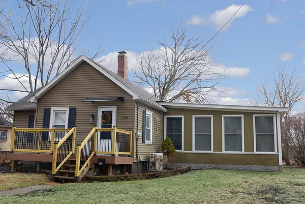 a view of house with a big yard and large trees