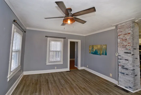 a view of an empty room with window and wooden floor