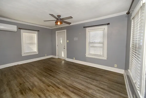 a view of an empty room with wooden floor and a window